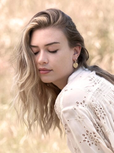 boucles d'oreilles cœur Linda - créoles dorées portées par une femme