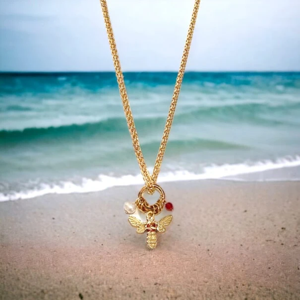 Collier amulette cuivrée abeille devant une plage - Bijou Gri-gri