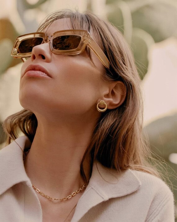 boucles d'oreilles gyptis. créoles dorées portées par une femme aux lunettes de soleil