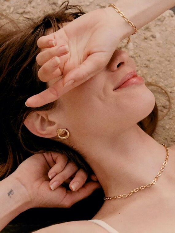 boucles d'oreilles gyptis. créoles dorées portées par une femme qui sourit