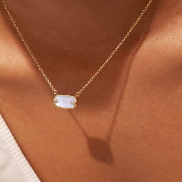Collier Sangha nacre. ras-de-cou doré à l'or fin, porté par une femme. Pendentif rectangulaire.