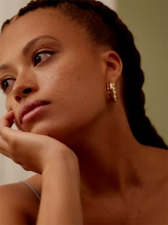 Grandes créoles vénus. Des bijoux à l'or fin portés par une jeune femme.