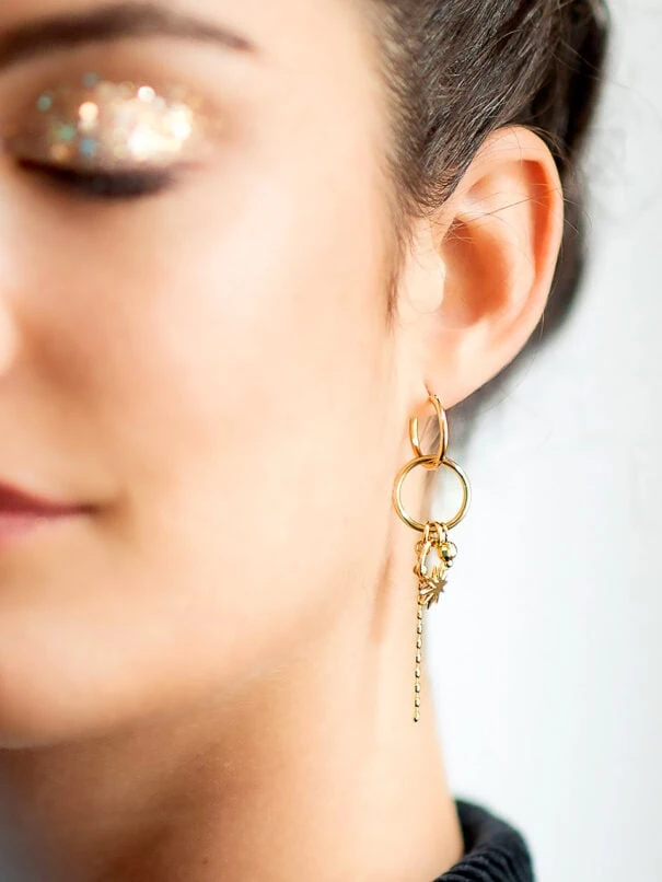 mono Boucle DREAM. Zoom sur la Boucle d'oreille pendante à l'unité, portée par une femme. Un bijou doré à l'or fin.