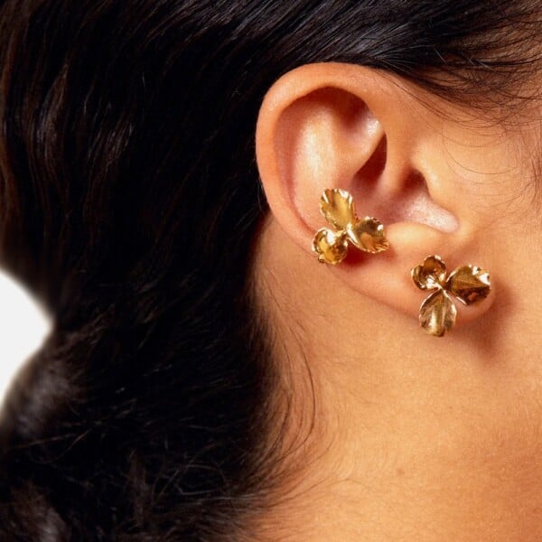 Earcuff Flora. Bague d'oreille en forme de fleur, portée par une femme. Bijou doré fait-main à paris.