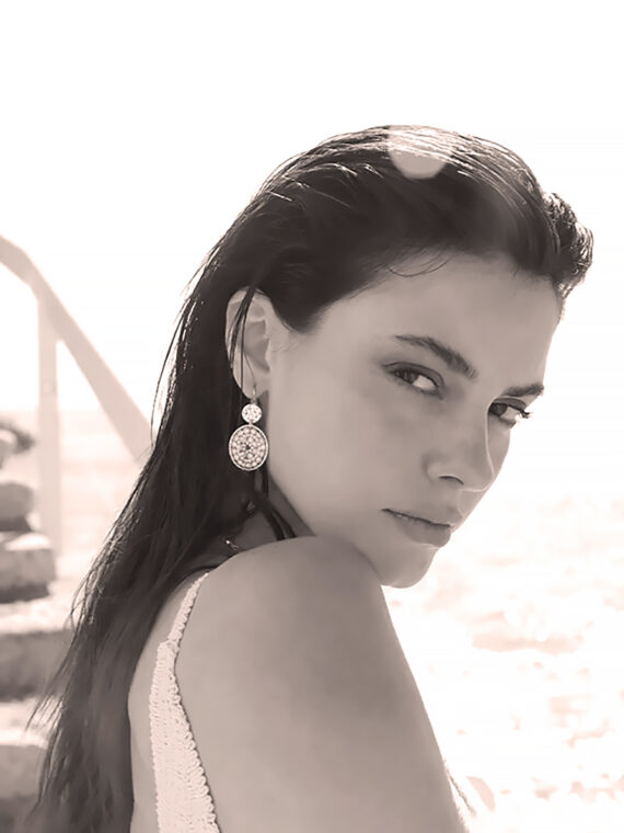 Boucles d'oreilles paradis sable portées par une femme. blanc et doré