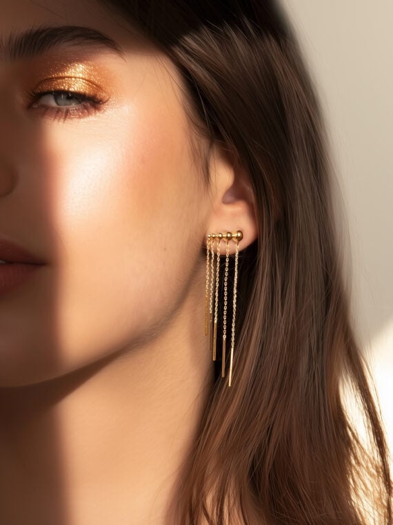 Boucles d'oreilles dorées élégantes portées par une femme. Forme chaînette cascade. Plaqué or.