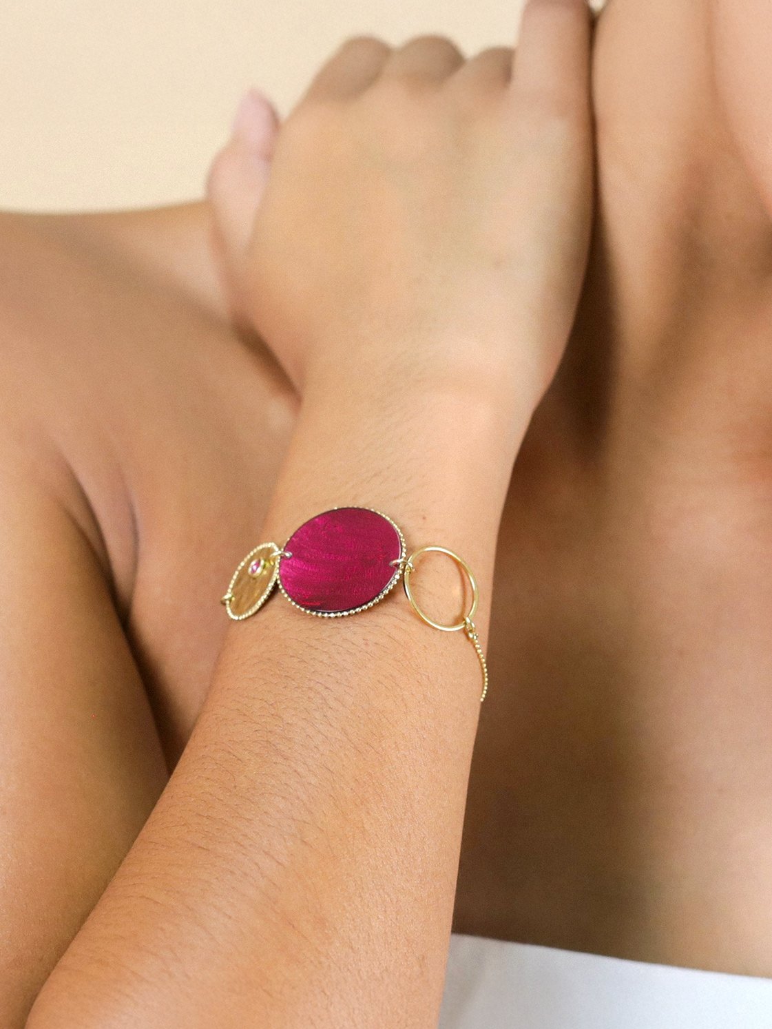 Femme portant le bracelet disque grenade Marly de Franck Herval, en capiz bordeaux effet velours, laiton doré à l’or fin et cristal Swarovski.
