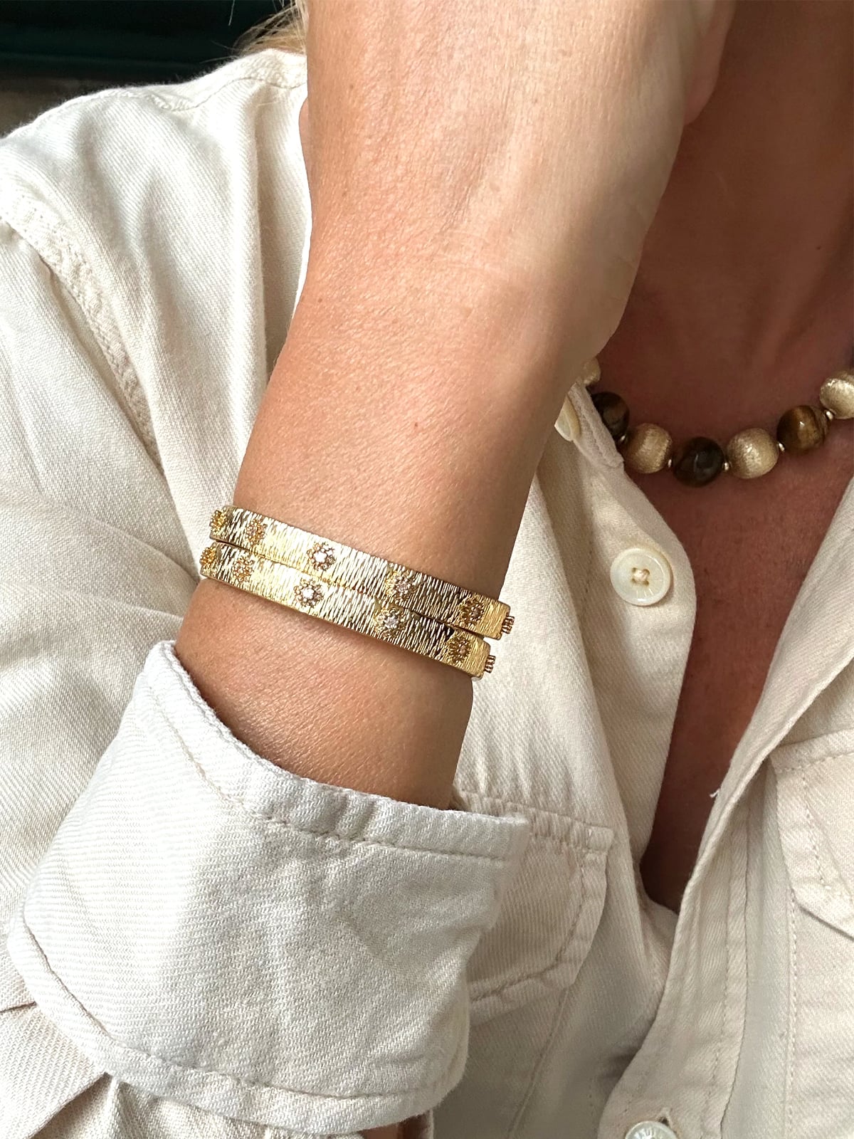 Jonc doré strié et strass Gabrielle 2 Jonc doré strié et strass Gabrielle, porté par une femme